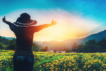 Fototapeta premium The woman stands on a field of yellow flowers. Sunset atmosphere