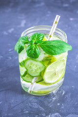 Sassy diet water. Cucumber, lemon, mint lemonade in glasses on grey background.