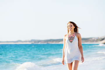 Fototapeta na wymiar Young woman walking along the beach