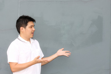 Asian man with white shirt over the grey wall amazing on something with copy space