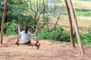 Lonely girl is sitting on the swing in the forest