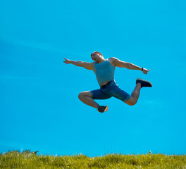 Jumping up guy. Background blue sky. Below the green grass