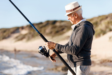 Senior man fishing at sea side