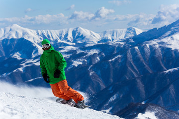Male snowboarder snowboarding on fresh snow on ski slope on Sunny winter day in the ski resort in...