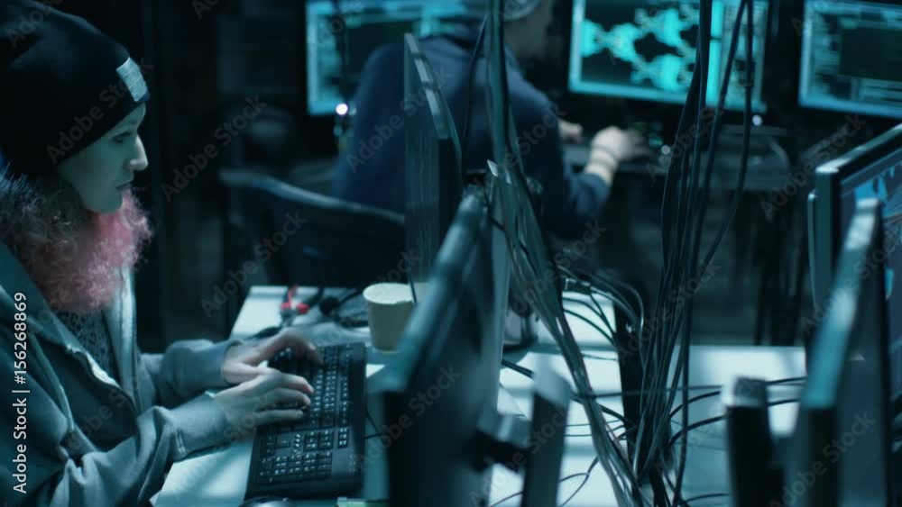 Poster Back View of Teenage Hacker Infecting with Virus Data Servers of Government Infrastructure. His Hideout is Dark with Many Monitors Around. Shot on RED EPIC-W 8K Helium Cinema Camera.