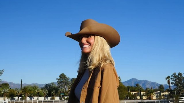 A beautiful mature cowgirl smiles while riding her horse