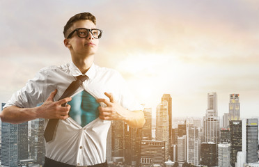 Business superhero. Young businessman showing super hero suit under his shirt down town on sunset.
