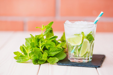 Fresh mojito cocktail in glass on wooden table. Mojito with mint leaves, lime and ice. Drink  ingredients for cocktail.