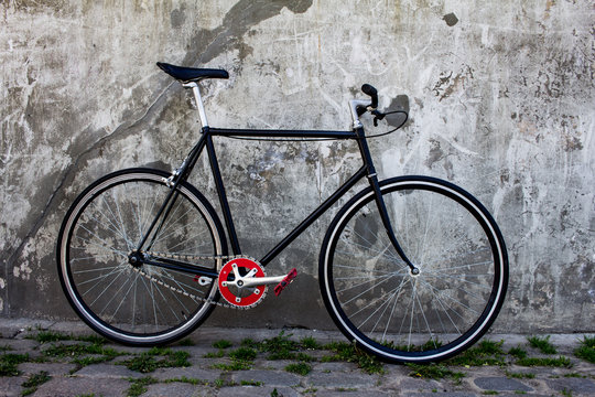 black hipster bicycle near the grey concrete wall
