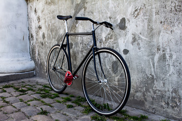 Fototapeta na wymiar black hipster bicycle near the grey concrete wall