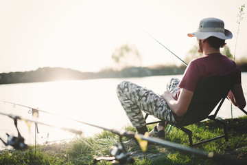 Young man fishing on lake at sunset enjoying hobby