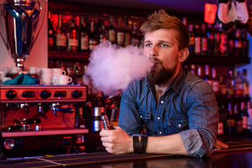 Vape. Vaping man in a cloud of vapor. Photo is taken in a vape bar.