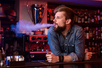 Vape. Vaping man in a cloud of vapor. Photo is taken in a vape bar.