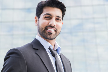 Smiling businessman or worker standing in suit near office building