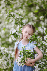 Cute little girl in blooming apple tree garden at spring