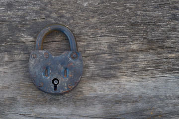 Grungy and rusted steel metal lock on a old wooden table background. Left position.