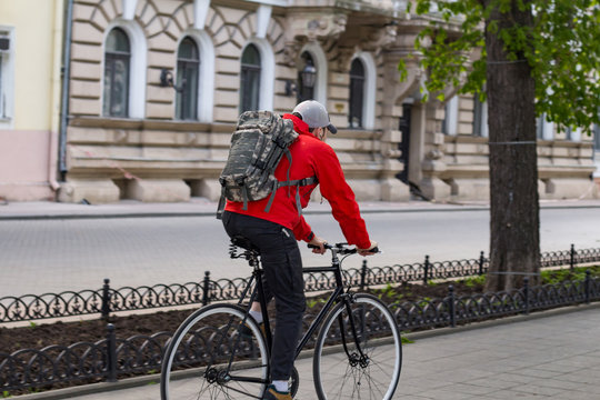 man ride on hipster black bike, young man in red jacket and camo backpack ride bicycle