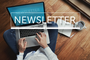 Top view of young woman sitting on the wooden floor with laptop and coffee with newsletter inscription in the foreground - obrazy, fototapety, plakaty