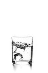 Cube of ice thrown into a glass with liquid