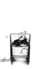 Cube of ice thrown into a glass with liquid