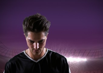 soccer player looking down, purple field lights background