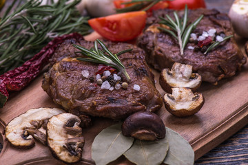  Beef Steak, salt, pepper, garlic, rosemary  on the  wooden board, background.