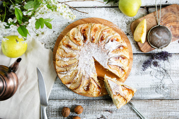 Apple pie on a wooden table with a teapot, top view, flat