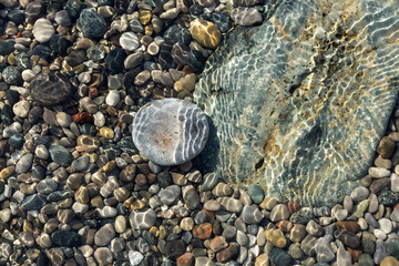 Ripples of the crystal clear shallow water surface, on a stony beach of Lake Huron, Ontario, Canada.