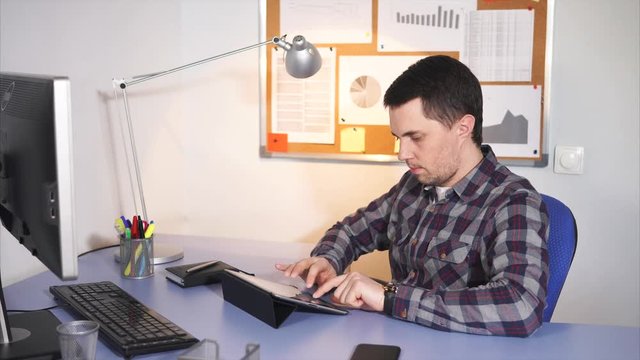 Office worker manager sitting at his work place, using a laptop. He sending different offers to his clients by email.