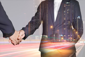 Double exposure of businesswomen handshake, light trails on the street and urban in the night as business, commitment, partnership and congratulation concept.