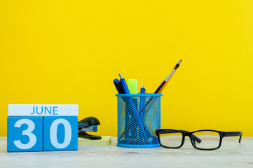 June 30th. Day 30 of month, calendar on yellow background with office suplies. Summer time at work