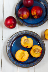 Nectarines, on dark blue plate. White wooden table.