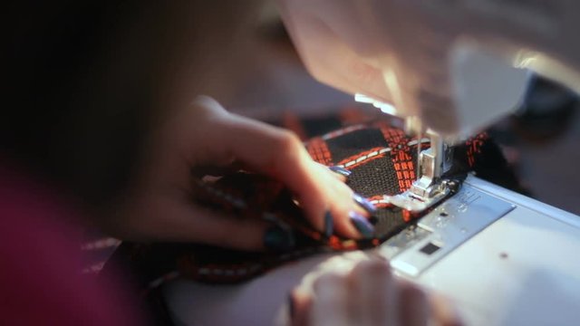 Close-up of woman's hands sewing an automatic overlock gadget. material crafting hobby cut macro tool design equipment process clothes trendy fashion working