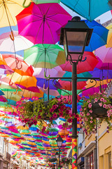 Fototapeta na wymiar The sky of colorful umbrellas.Street with umbrellas.Umbrella Sky Project in Agueda, Aveiro district, Portugal.Street decoration. Street decorated with colored umbrellas.