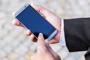 Man in black suit holds mobile phone in his hand