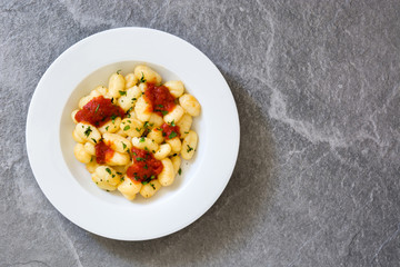 Gnocchi with tomato sauce on gray stone
