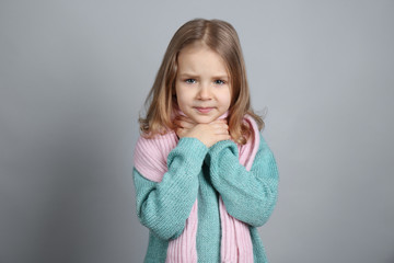 Little ill girl with sore throat on color background. Concept of allergy