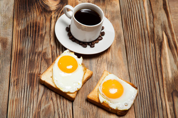 Cup with coffee, toast and eggs on a wooden table