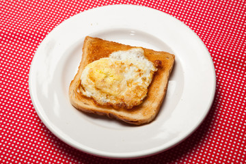 Toast and egg on a plate on a red table