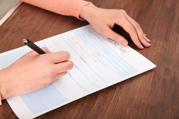 Woman filling in resume form on table. Job interview concept