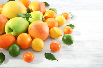 Appetizing fresh citrus fruits and apples on white wooden background