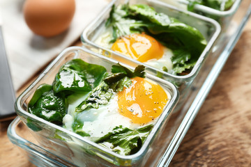 Delicious eggs Florentine in glass baking dishes on wooden table