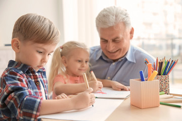Cute little boy painting together with his  sister and grandfather