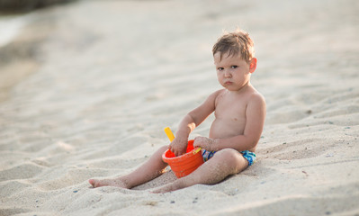 Caucasian boy with toys in sandy beach