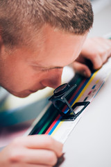 Worker in printing and press centar uses a magnifying glass