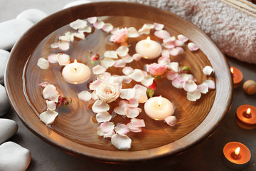Beautiful spa composition with flower petals and candles on water