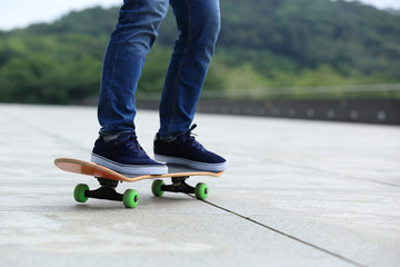 Fototapeta na wymiar Skateboarder legs skateboarding at city