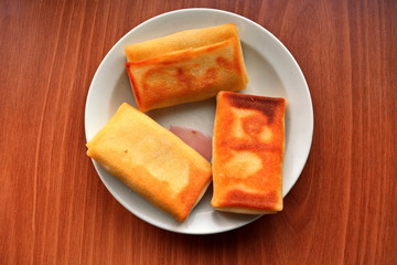 three thick, oily solid piece pancake with cottage cheese and natural berry syrup jam on white plate on wooden table in center