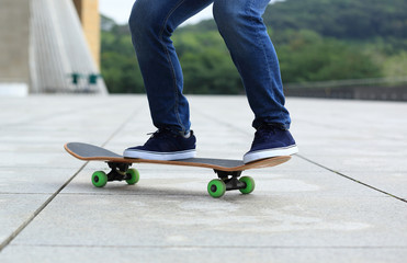 Fototapeta na wymiar Skateboarder legs skateboarding at city