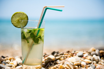 Summer mojito drink with blur beach on background. Copyspace for text
